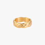 Close-up of an 18K gold-plated twisted band ring with dimensional braided pattern on cream background.
